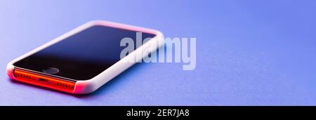 Ein modernes Smartphone liegt auf einer blauen Oberfläche oder Tisch in Perspektive mit einem Ort für Text. Stockfoto