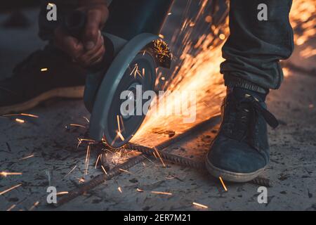 Nahaufnahme der Hot Bright Sparks Fliegen Sie aus dem Stahlschneider heraus. Harte Arbeit. Jobs Mit Blauem Kragen. Stockfoto