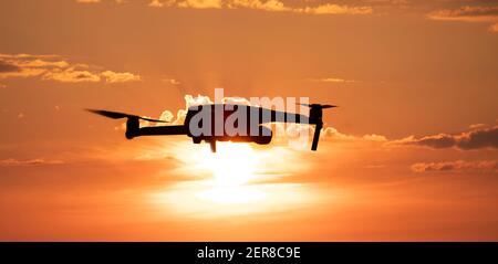 Quadcopter oder Drohne auf einem Sonnenuntergang Hintergrund Stockfoto