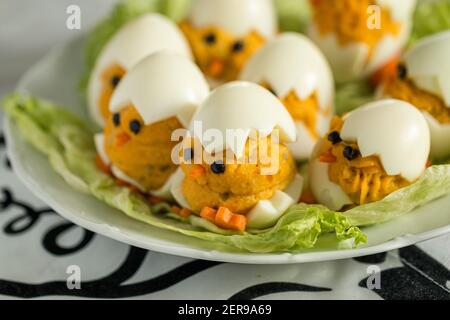 Vorspeise gekochte gefüllte dekorative Eier in Form von kleinen Küken auf Salat gelegt. Osterdekoration. Stockfoto