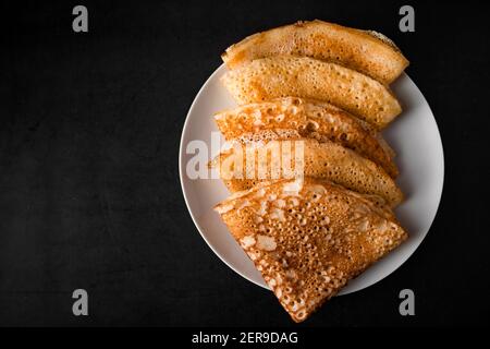 Leckere Crepes auf einem Teller auf schwarzem Hintergrund. Traditionelle russische Küche. Ort für Ihren Text. Stockfoto