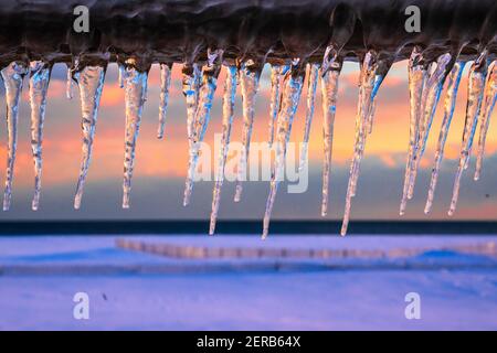Eiszapfen an einem Wintertag mit buntem Sonnenuntergang Im Hintergrund Stockfoto