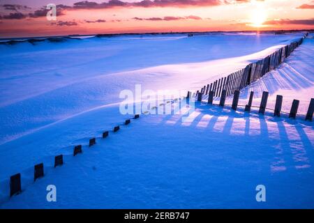 Winterszene unter farbigem Himmel bei Sonnenuntergang am schneebedeckten Strand. Jones Beach State Park, Long Island NY Stockfoto