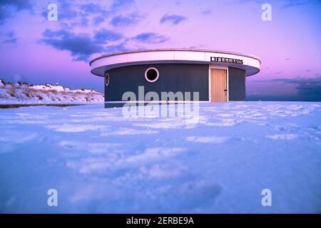 Winterszene unter farbigem Himmel bei Sonnenuntergang am schneebedeckten Strand. Jones Beach State Park, Long Island NY Stockfoto