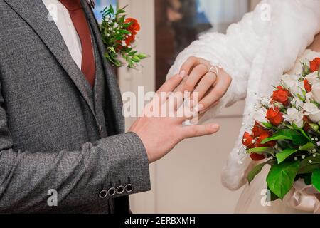Die Hand der Braut legt den Ehering auf die Daumen des Bräutigams. Stockfoto