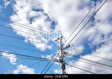 Nahaufnahme der Power-Säule an einem Sommertag. Stromlinienpfosten mit Stromkabeln gegen einen blauen Himmel Stockfoto