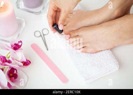 Fröhliche Mädchen Tun Nägel Machen Pediküre Sitzen Im Bett Drinnen. Stockfoto