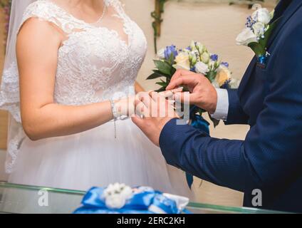 Teilen von Eheringen. Bräutigam legt Ring auf den Finger der Braut. Stockfoto