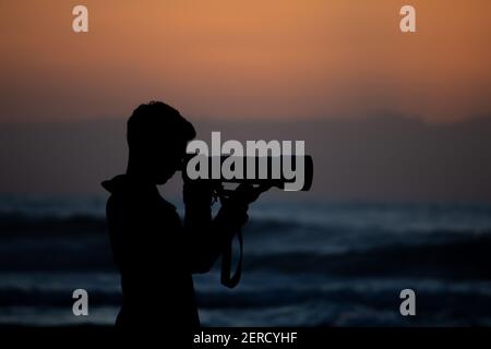 Erstaunliche Shilouette von einem Fotografen, der ein Bild an der Strand bei Sonnenuntergang Stockfoto