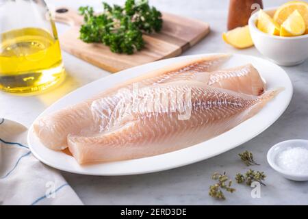 Frische isländische Haddock-Filets auf einem Teller mit Zitrone und Petersilie. Stockfoto