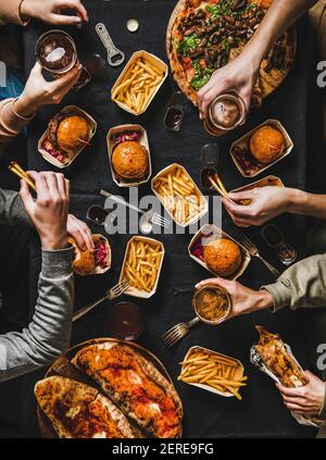 Lockdown Familie Fast Food Abendessen von Lieferservice. Flat-Lay von Freunden, die Quarantäne Home Party mit Burger, Pommes, Sandwiches, Pizza, Bier o Stockfoto