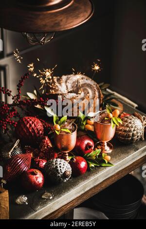 Weihnachten oder Thanksgiving Day festliche hausgemachte gebündelt Kuchen mit Wunderkerzen Und Winter Eis erfrischende Zitruscocktails in Kupfer-Becher auf Küche zählen Stockfoto