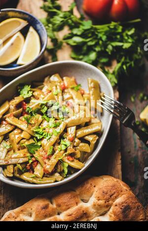 Türkische traditionelle geschmorte grüne Beens Vorspeise mit Tomaten und Olivenöl über Holz rustikalen Tisch, Draufsicht, seelctive Fokus. Türkische regionale Küche Stockfoto