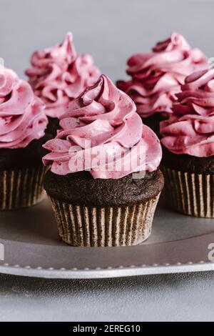 Schokoladen-Cupcakes mit rosa Marshmallow-Zuckerguss auf der Oberseite. Serviert auf einem silbernen Teller. Stockfoto