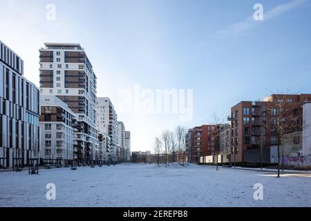 Sonniger Blick im Freien auf den Berty-Albrecht-Park, der von Schnee bedeckt und umgeben ist mit modernen Wohn- und Bürogebäuden in der Wintersaison. Stockfoto