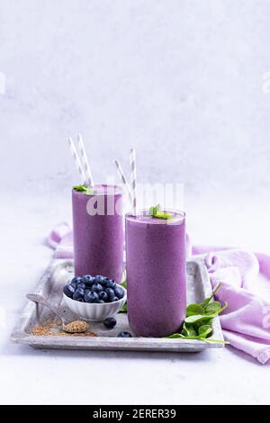 Zwei gesunde Heidelbeer-Smoothies auf einem Tablett gegen ein Licht Hintergrund Stockfoto