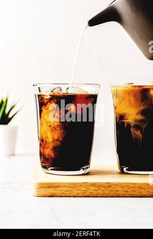 Eiskaffee und Milch werden auf einem Schneidebrett serviert. Stockfoto