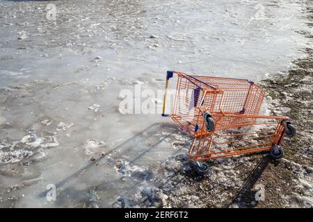 Kaputter Einkaufswagen auf eisigen Böden im Freien. Stockfoto