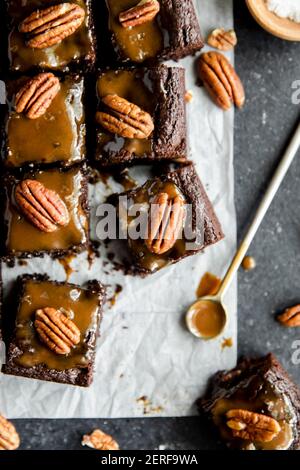 Turtle Brownies mit gesalzenem Karamell und Pecan Topping in einem Flachlay. Stockfoto