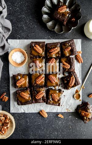 Turtle Brownies mit gesalzenem Karamell und Pecan Topping in einem Flachlay. Stockfoto