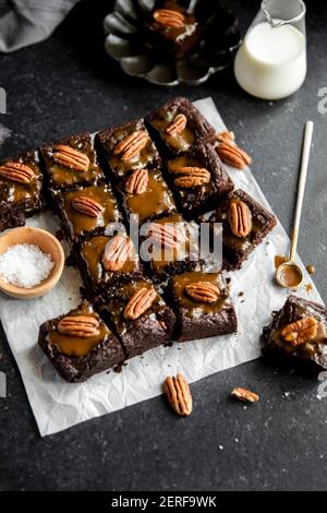 Turtle Brownies mit gesalzenem Karamell und Pecan Topping in einem Flachlay. Stockfoto