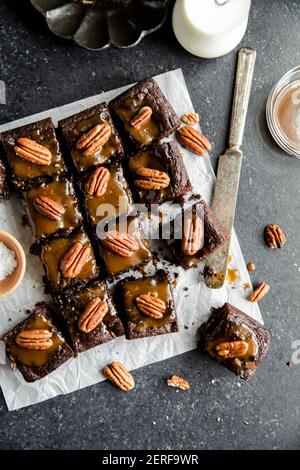 Turtle Brownies mit gesalzenem Karamell und Pecan Topping in einem Flachlay. Stockfoto