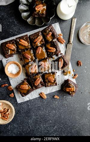 Turtle Brownies mit gesalzenem Karamell und Pecan Topping in einem Flachlay. Stockfoto