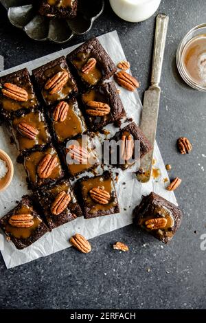 Turtle Brownies mit gesalzenem Karamell und Pecan Topping in einem Flachlay. Stockfoto