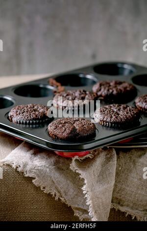 Frisch gebackene hausgemachte Schokolade Cupcakes Muffins in Form zum Kochen stehen auf Küchentisch mit Tischdecke. Hausbäckerei Stockfoto