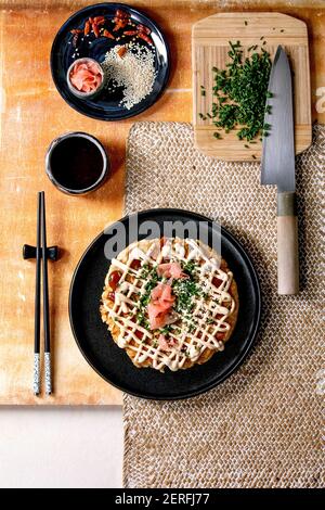 Hausgemachte japanische Fast Food Okonomiyaki Kohl Pfannkuchen von Frühlingszwiebel, eingelegter Ingwer, Mayo-Sauce auf schwarzem Keramikplatte mit Essstäbchen a dekoriert Stockfoto