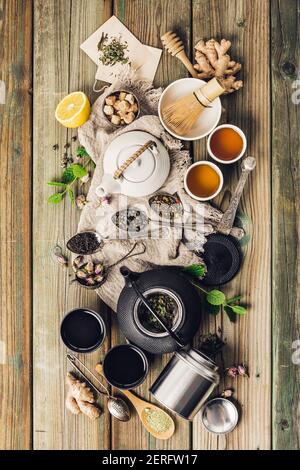 Verschiedene Tee und Teekannen Zusammensetzung, getrocknete Kräuter-, Grün-, Schwarz-Tee und Matcha-Tee auf Holztisch Hintergrund, flach legen Stockfoto