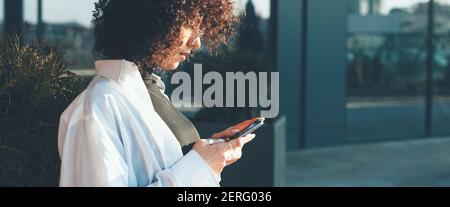 Seitenansicht Foto einer lockigen haarigen Frau im Chat Mobil mit Freunden Stockfoto