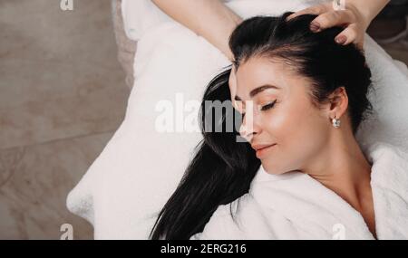 Brunette Dame mit einem Kopf Massage-Sitzung liegend mit geschlossen Augen auf der Spa-Couch Stockfoto