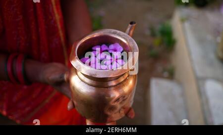 Kupferkalsch voller heiligem Wasser und duftenden Blumen. Heilige Kalasch oder Becher, um Gott anzubeten. Hindu Religion Konzept. Stockfoto
