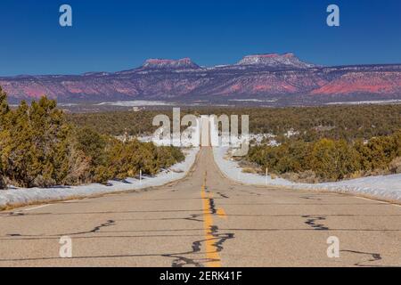 Panoramablick auf leere und endlose Straße mit Bären Ohren Berge im Hintergrund im Winter Stockfoto