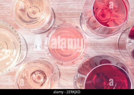 Wein, weiß, rosa und rot, in verschiedenen Gläsern, Aufnahme von oben auf einem hölzernen Hintergrund, getöntes Bild Stockfoto