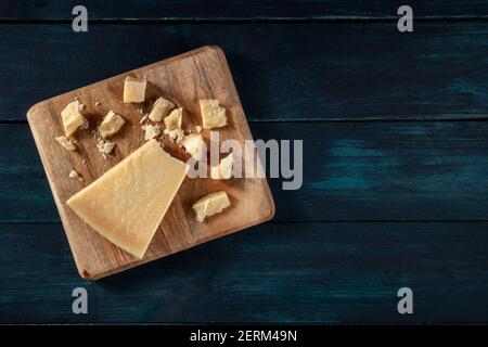 Zerbröckelter Parmesan-Käse, von oben auf einem dunkelblauen Holzhintergrund mit einem Platz für Text geschossen Stockfoto