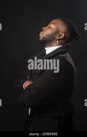 Schwarzer Mann im Profil, sehr ernst und mit gekreuzten Armen. Stockfoto