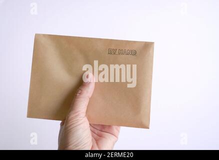 Frau mit einem braunen Umschlag mit Gummistempel, von Hand an der Spitze. Auf weißem Hintergrund. Stockfoto