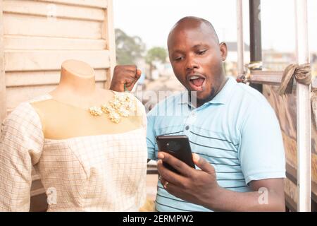 afrikanischer Mann, der glücklich in sein Telefon schaut Stockfoto