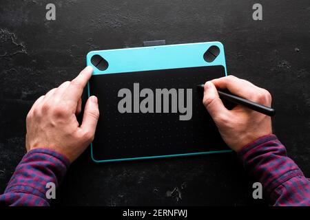 Mann zeichnet auf Grafik-Tablet auf schwarzem Hintergrund Stockfoto