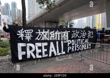 Unterstützer von pro-demokratischen Aktivisten halten vor dem West Kowloon Court ein Transparent mit der Aufschrift "Freie politische Gefangene". 47 prodemokratische Aktivisten Hongkongs, die wegen Verschwörung zur Unterwanderung der Staatsmacht nach dem nationalen Sicherheitsgesetz angeklagt sind, nehmen an ihrer ersten Gerichtsverhandlung Teil, während sich Tausende von Unterstützern vor dem Gericht versammeln, um ihre Solidarität auszudrücken. Stockfoto