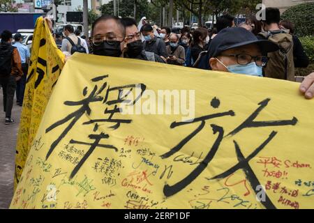 Unterstützer von pro-demokratischen Aktivisten halten vor dem West Kowloon Court ein Transparent mit der Aufschrift "Alle politischen Gefangenen freilassen". 47 prodemokratische Aktivisten Hongkongs, die wegen Verschwörung zur Unterwanderung der Staatsmacht nach dem nationalen Sicherheitsgesetz angeklagt sind, nehmen an ihrer ersten Gerichtsverhandlung Teil, während sich Tausende von Unterstützern vor dem Gericht versammeln, um ihre Solidarität auszudrücken. Stockfoto