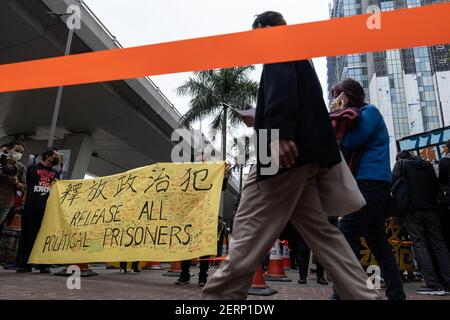 Unterstützer von pro-demokratischen Aktivisten halten vor dem West Kowloon Court ein Transparent mit der Aufschrift "Alle politischen Gefangenen freilassen". 47 prodemokratische Aktivisten Hongkongs, die wegen Verschwörung zur Unterwanderung der Staatsmacht nach dem nationalen Sicherheitsgesetz angeklagt sind, nehmen an ihrer ersten Gerichtsverhandlung Teil, während sich Tausende von Unterstützern vor dem Gericht versammeln, um ihre Solidarität auszudrücken. Stockfoto