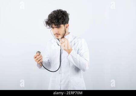 Porträt eines männlichen Arztes, der ein Stethoskop hält und zuhört Stockfoto