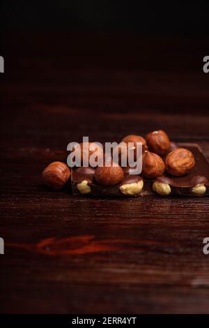 Schokoladenstücke und Nüsse auf dunklem Hintergrund Stockfoto