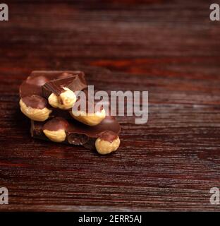 Schokoladenstücke und Nüsse auf dunklem Hintergrund Stockfoto