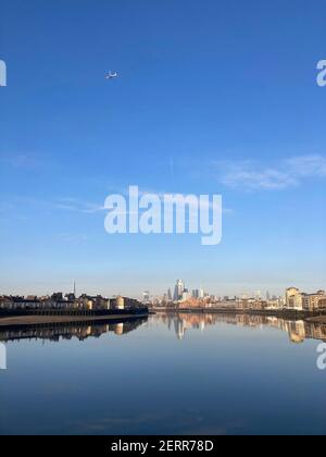 Am frühen Morgen kann ein Flugzeug über der City of London während der Sperre gesehen werden, die Themse von Canary Wharf Riverside aus gesehen. Februar 2021 Stockfoto