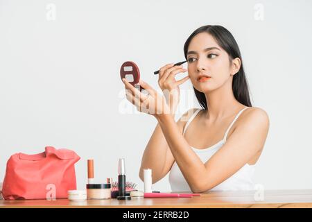Gemischte Rasse asiatische Frau setzen Augenliner auf Augenlid auf Weißer Hintergrund Stockfoto
