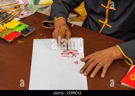 Nahaufnahme Foto der menschlichen Hand mit chinesischen Kalligraphie Pinsel Und Malerei Stockfoto